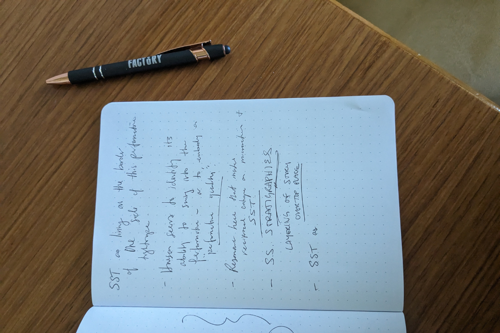 A pen sits next to a notebook with scribbles about site-specific theatre.